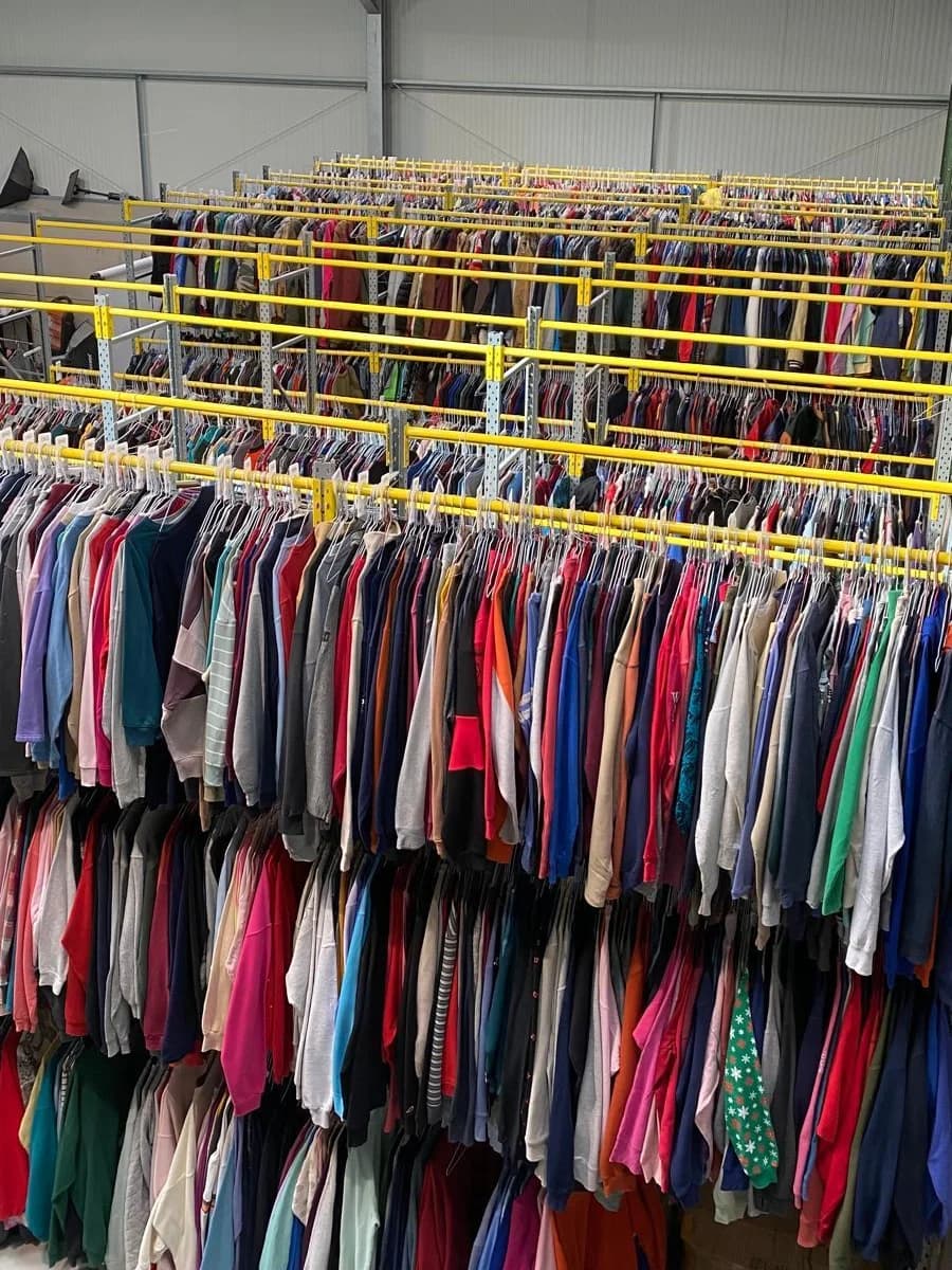 Our first warehouse, full: rows of yellow rails packed with vintage clothing